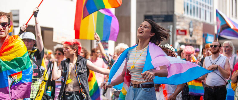 Bristol pride 2022, a group of people walking down the street with pride flags, they are smiling